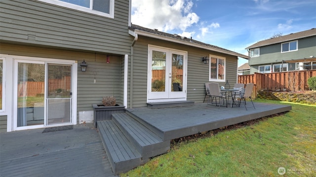 wooden terrace with french doors, fence, and a lawn