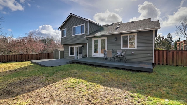 rear view of house with french doors, a fenced backyard, a deck, and a shed