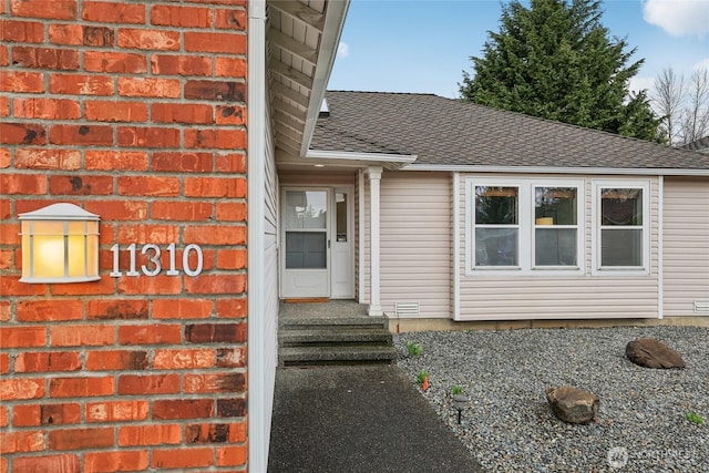 doorway to property with a shingled roof