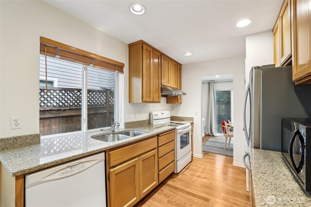 kitchen featuring under cabinet range hood, recessed lighting, light wood-style floors, white appliances, and a sink