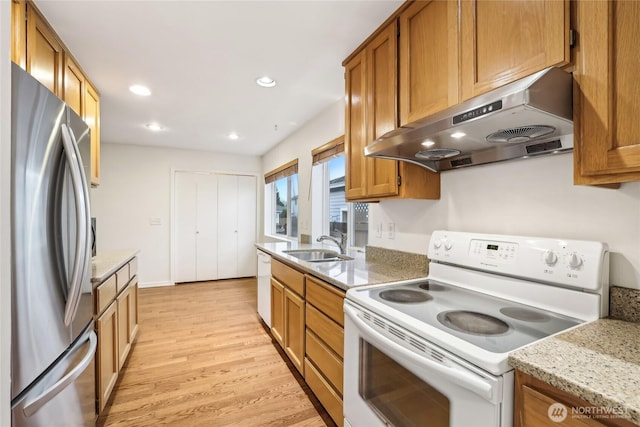 kitchen with under cabinet range hood, recessed lighting, light wood-style flooring, white appliances, and a sink