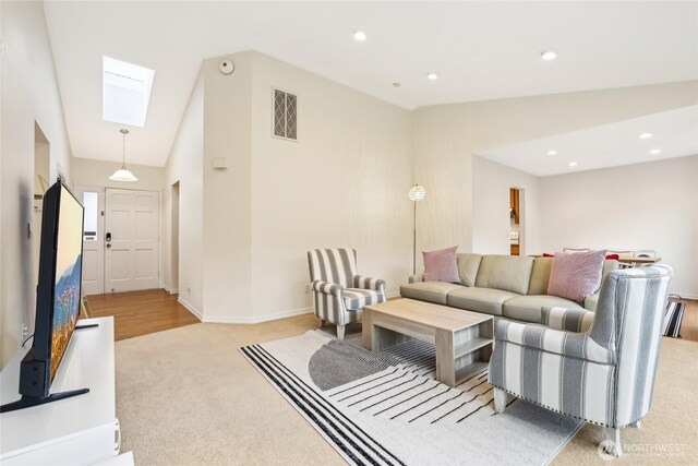 living room with lofted ceiling with skylight, recessed lighting, carpet, and visible vents