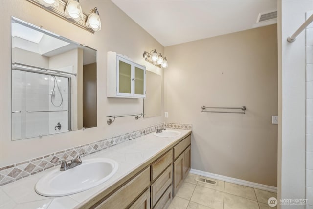 bathroom featuring double vanity, baseboards, a shower with shower door, and a sink