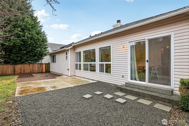 back of property featuring a patio area, fence, and a chimney