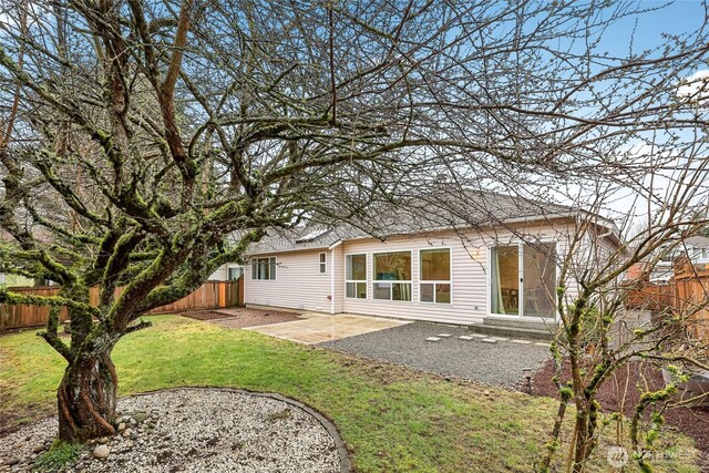 back of property featuring a patio, a yard, and fence