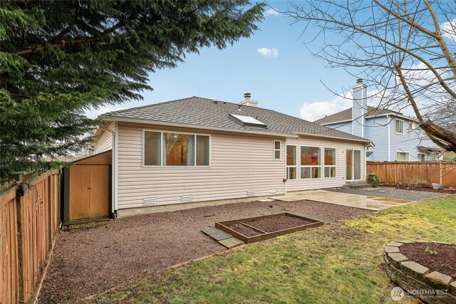 rear view of property with a lawn, entry steps, a patio, a fenced backyard, and roof with shingles