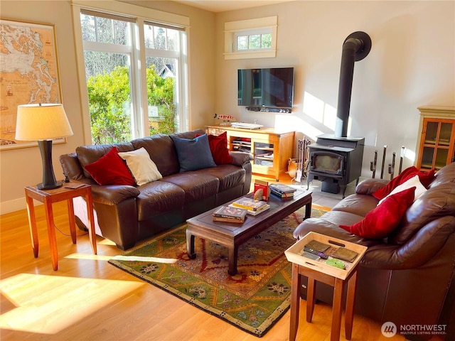 living area with light wood-type flooring, a wood stove, and baseboards