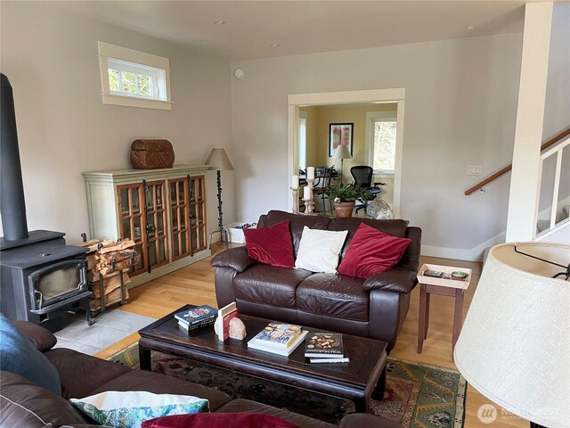 living room with wood finished floors, a wood stove, and baseboards