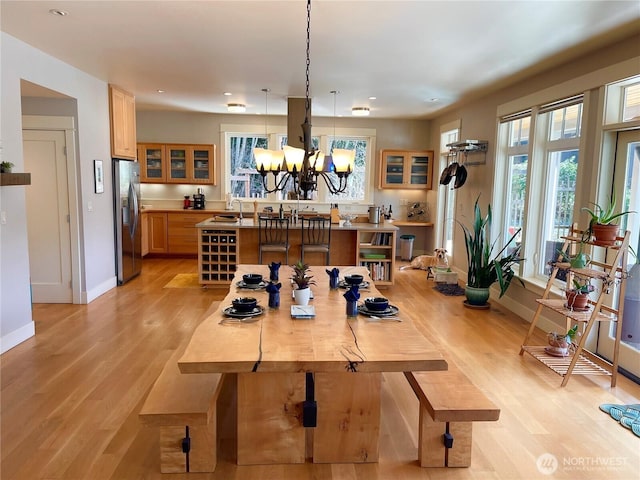 dining area with light wood-style floors, a chandelier, and baseboards