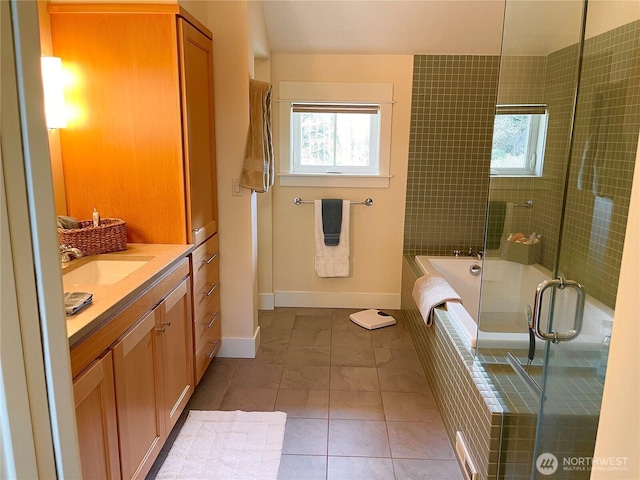 full bath featuring plenty of natural light, a tile shower, baseboards, and a bath