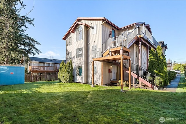 rear view of house with crawl space, a lawn, and stairs