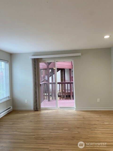 unfurnished room featuring a baseboard heating unit, recessed lighting, wood finished floors, and baseboards