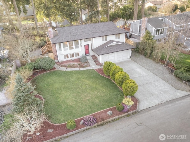 view of front of house with a garage, concrete driveway, a chimney, roof with shingles, and a front lawn