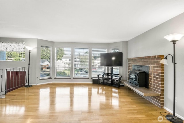 unfurnished living room featuring a wood stove, light wood-type flooring, and baseboards