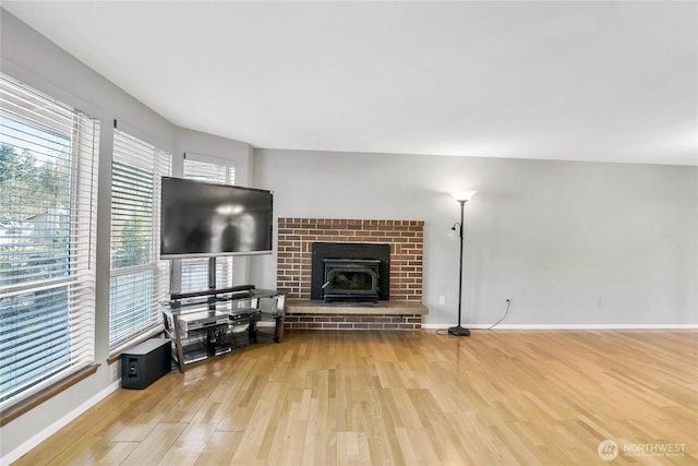 living area featuring a wood stove, baseboards, and wood finished floors