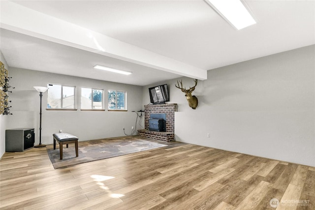 interior space featuring a wood stove, beamed ceiling, and light wood-style flooring