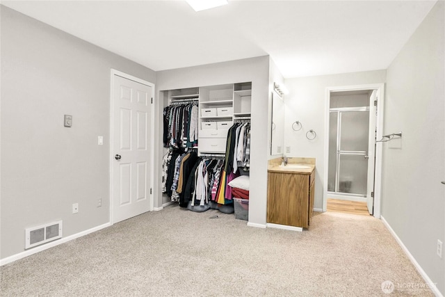 interior space with baseboards, visible vents, light colored carpet, ensuite bath, and a closet