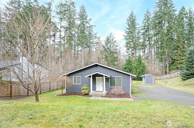 view of front of property with a front lawn, a storage shed, an outdoor structure, and fence