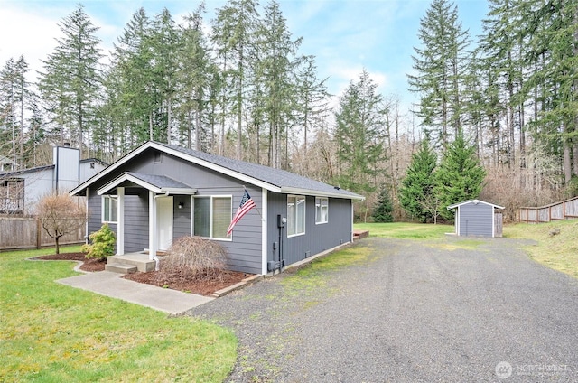 view of front of house with a storage unit, an outbuilding, a front yard, and fence