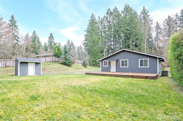 view of yard featuring an outbuilding, a deck, a storage shed, and central AC