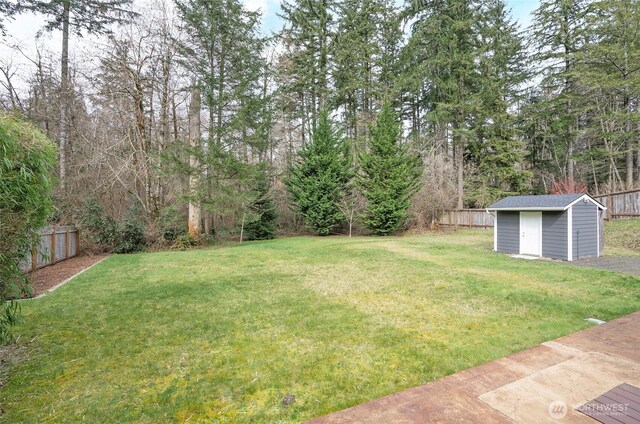 view of yard featuring a storage shed, an outbuilding, and fence