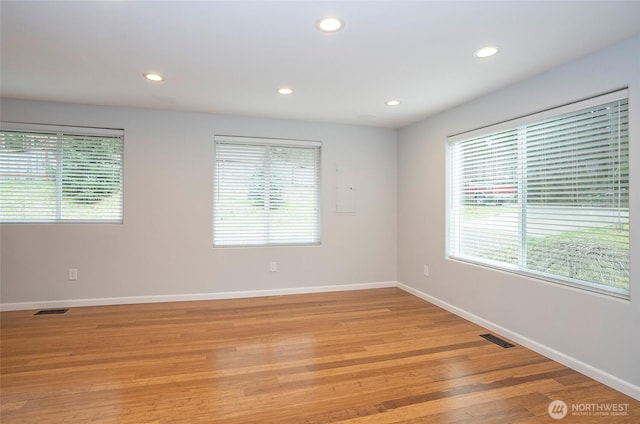 unfurnished room featuring light wood-style flooring, baseboards, visible vents, and a wealth of natural light