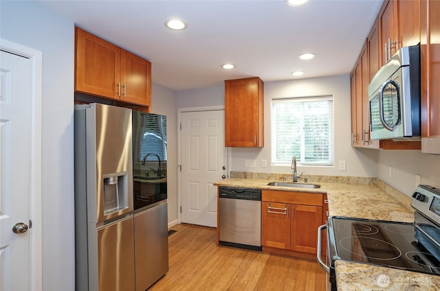 kitchen with light wood-type flooring, brown cabinets, a sink, recessed lighting, and stainless steel appliances