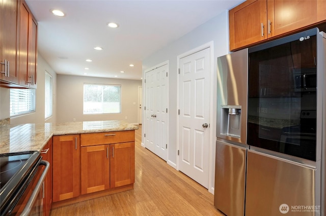 kitchen featuring light stone counters, brown cabinets, a peninsula, and light wood-type flooring