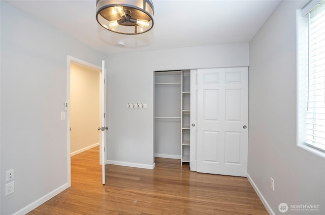 unfurnished bedroom featuring a closet, baseboards, and wood finished floors