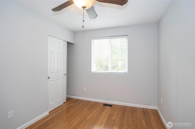 spare room featuring ceiling fan, visible vents, baseboards, and wood finished floors