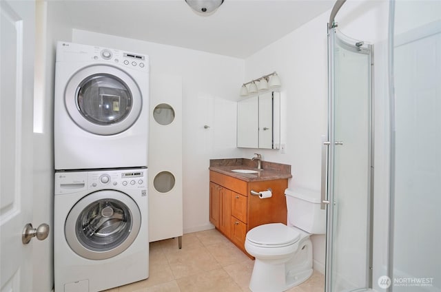 washroom with a sink, stacked washer and dryer, laundry area, and light tile patterned floors