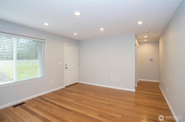 spare room featuring visible vents, baseboards, and light wood finished floors