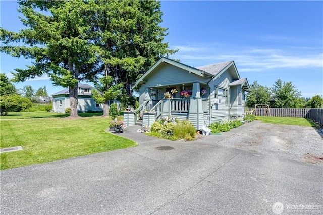 view of front of house with covered porch, a front yard, and fence