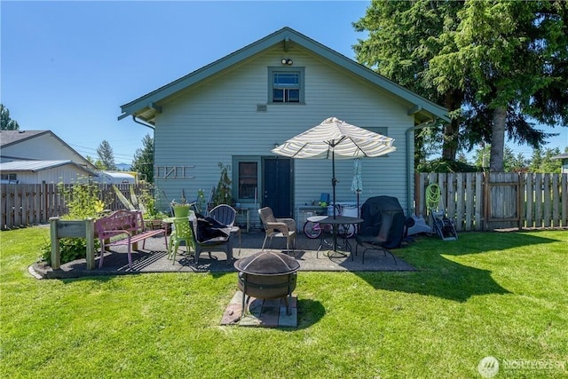 rear view of house featuring a patio area, a fenced backyard, a fire pit, and a yard