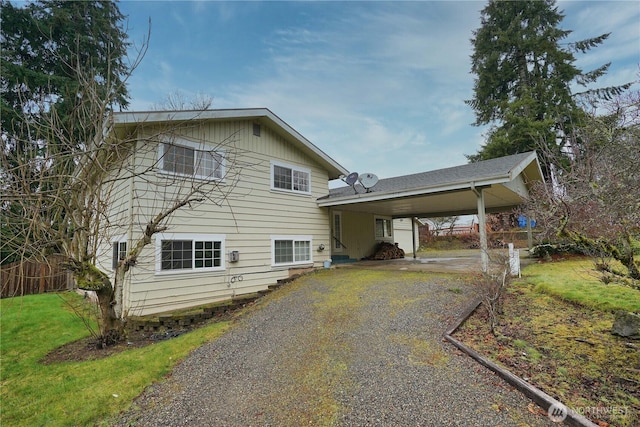 view of front of property with gravel driveway, a front lawn, and a carport