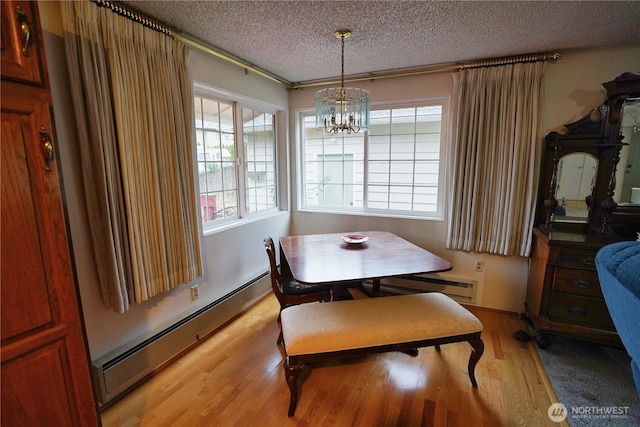 dining area featuring a notable chandelier, a baseboard radiator, a baseboard heating unit, a textured ceiling, and light wood-type flooring