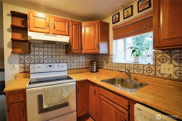 kitchen with white appliances, under cabinet range hood, light countertops, and a sink