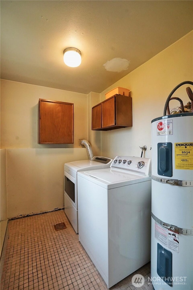 washroom with water heater, light tile patterned floors, cabinet space, and washer and dryer