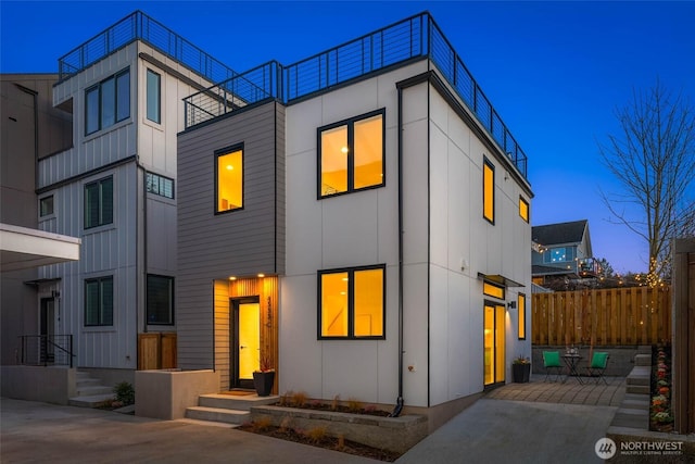 contemporary home with board and batten siding, a patio area, and fence