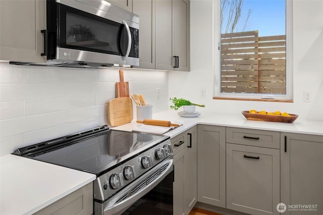 kitchen featuring appliances with stainless steel finishes, light countertops, decorative backsplash, and gray cabinetry