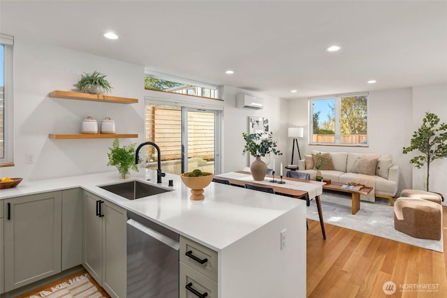 kitchen with a peninsula, a sink, gray cabinets, an AC wall unit, and stainless steel dishwasher