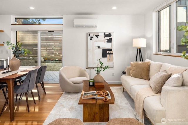 living room featuring recessed lighting, a wall mounted air conditioner, and light wood-style flooring