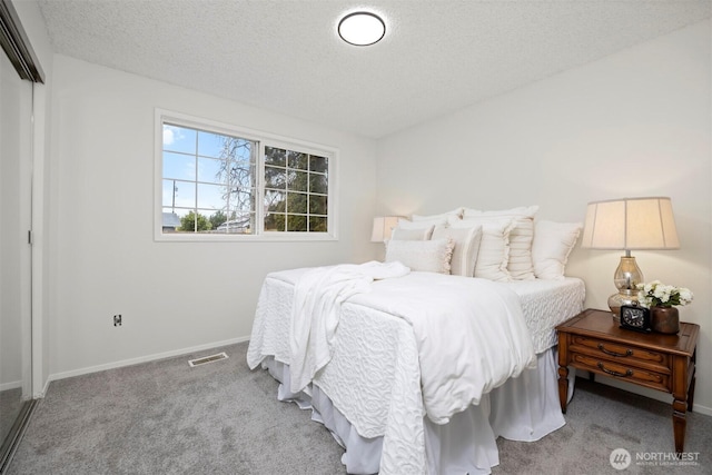 carpeted bedroom featuring baseboards, visible vents, a closet, and a textured ceiling