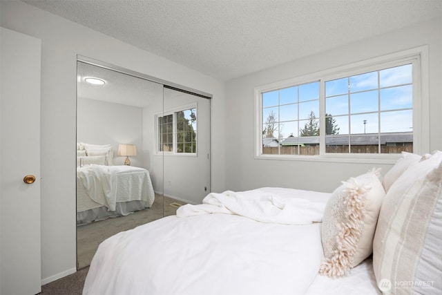 carpeted bedroom featuring baseboards, a closet, and a textured ceiling