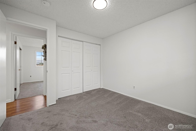 unfurnished bedroom featuring carpet flooring, baseboards, a closet, and a textured ceiling