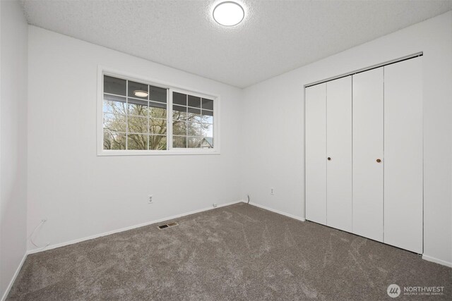 unfurnished bedroom featuring visible vents, a textured ceiling, a closet, carpet floors, and baseboards