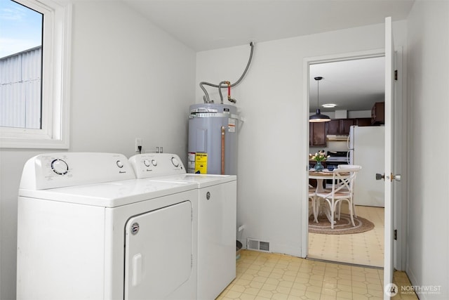 clothes washing area with light floors, visible vents, washing machine and clothes dryer, laundry area, and water heater