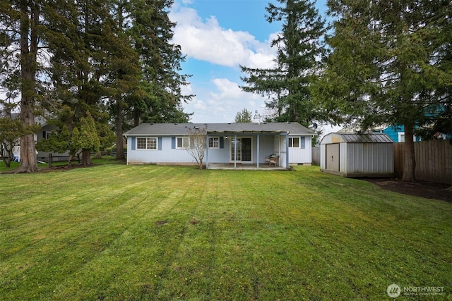 back of property with fence, crawl space, a lawn, an outbuilding, and a storage unit