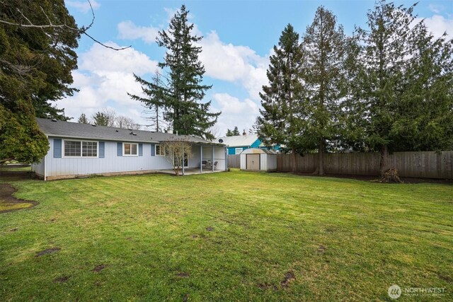 view of yard featuring a storage shed, an outbuilding, and a fenced backyard