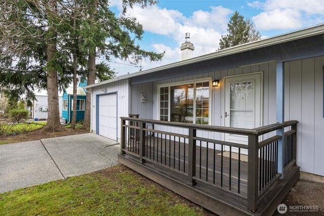 exterior space with a chimney, covered porch, and concrete driveway